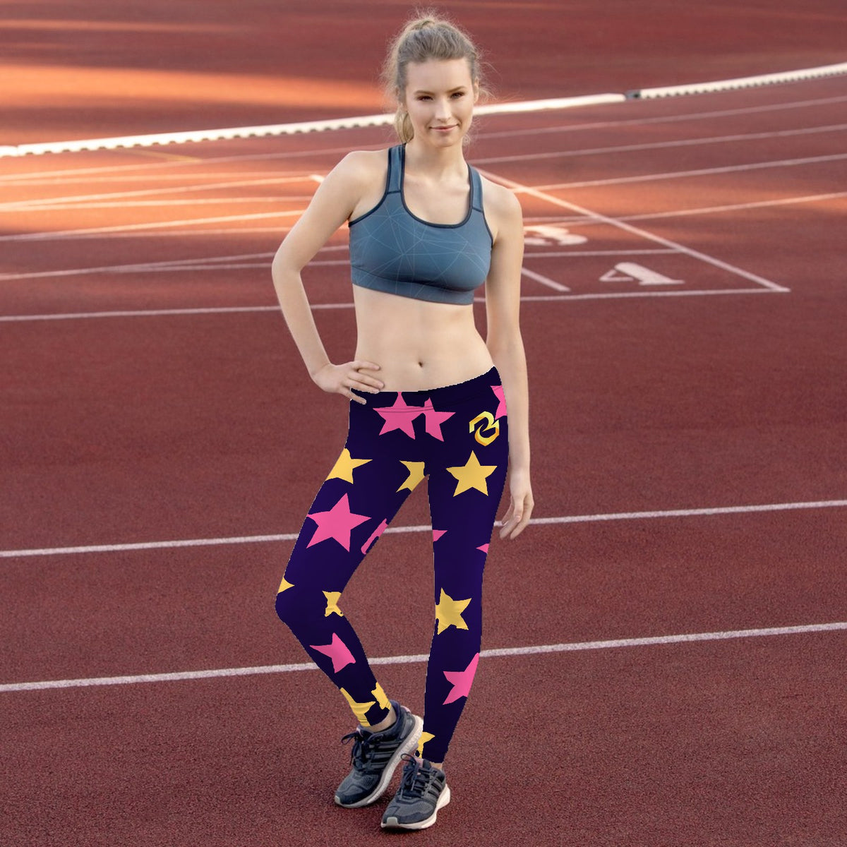 Custom all over print leggings with gold and pink stars, worn on a running track